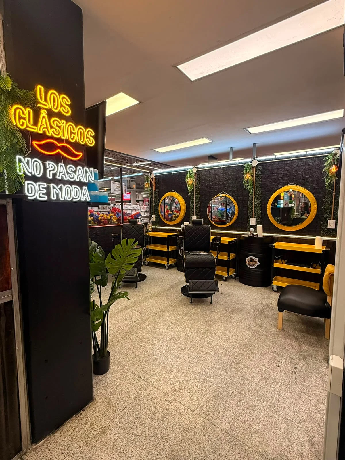 Interior de barbería Clásicos con sillones, espejos amarillos y mobiliario
