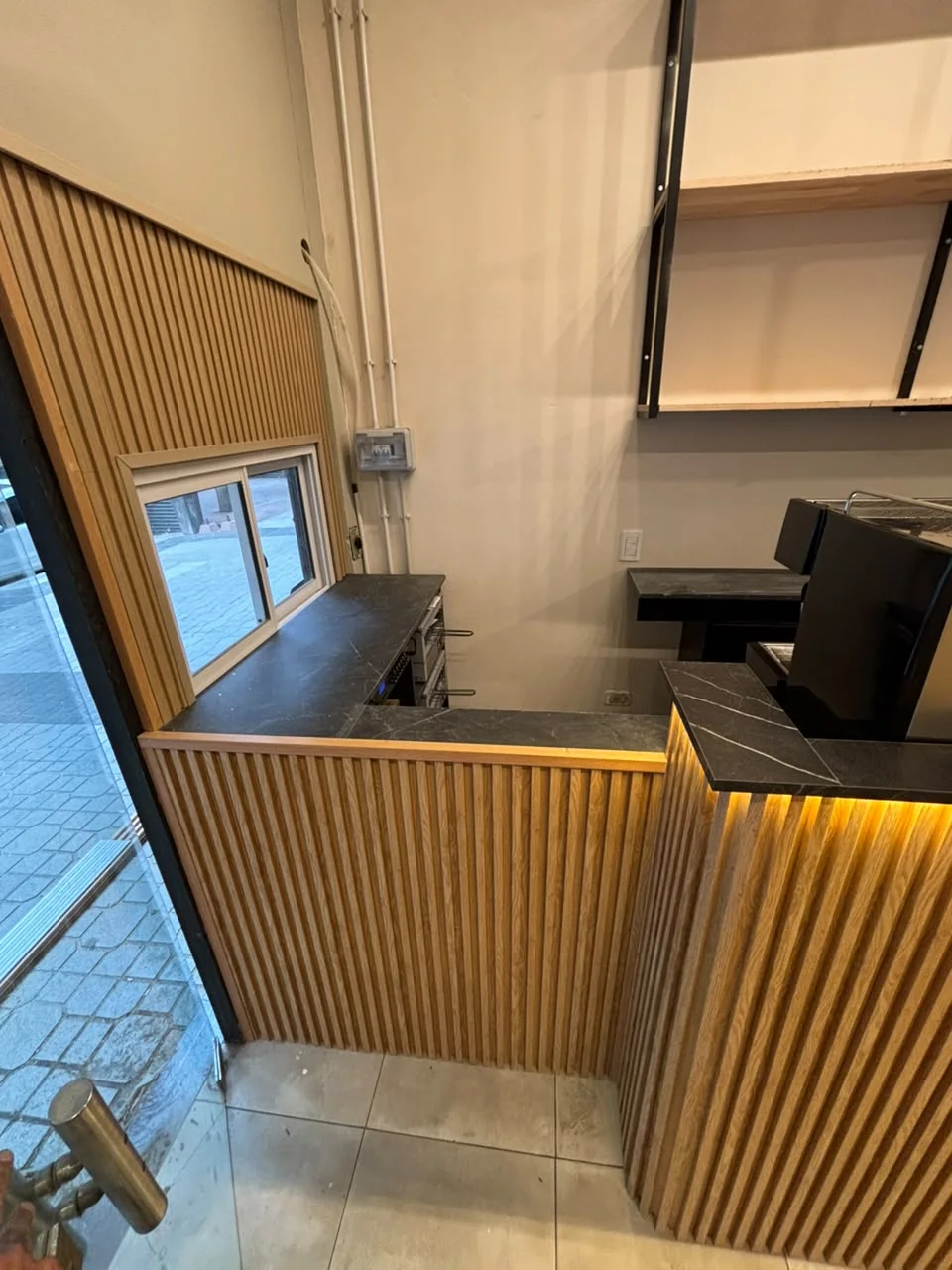 Detalle de barra con listones verticales de madera y mesada oscura
